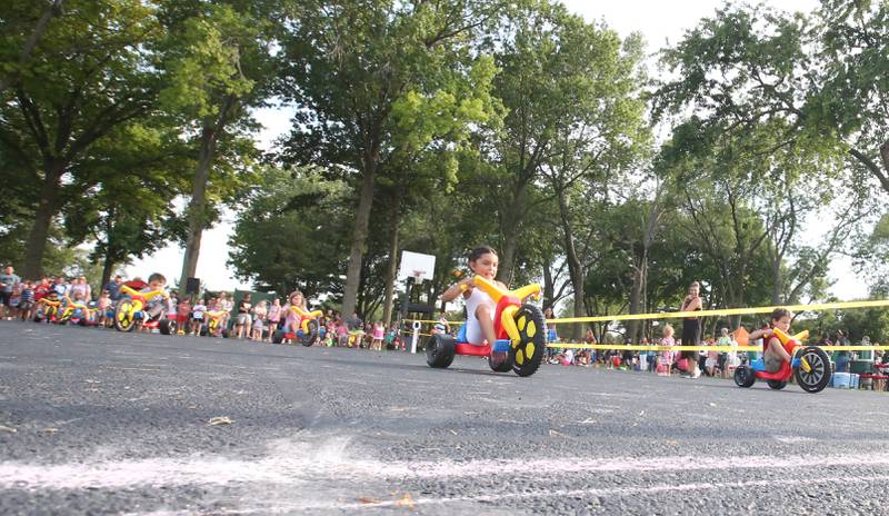 Kids petal tricycles down the straight away during the Big Wheel Race for the National Night Out event on Tuesday, Aug. 1, 2023 in Spring Valley.