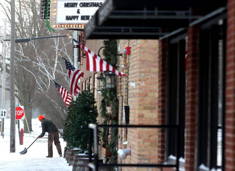 Mike Harrah clears the sidewalk near the D5 Ranges in Marengo Friday morning after Thursday snow was followed by bitter cold  on Friday.