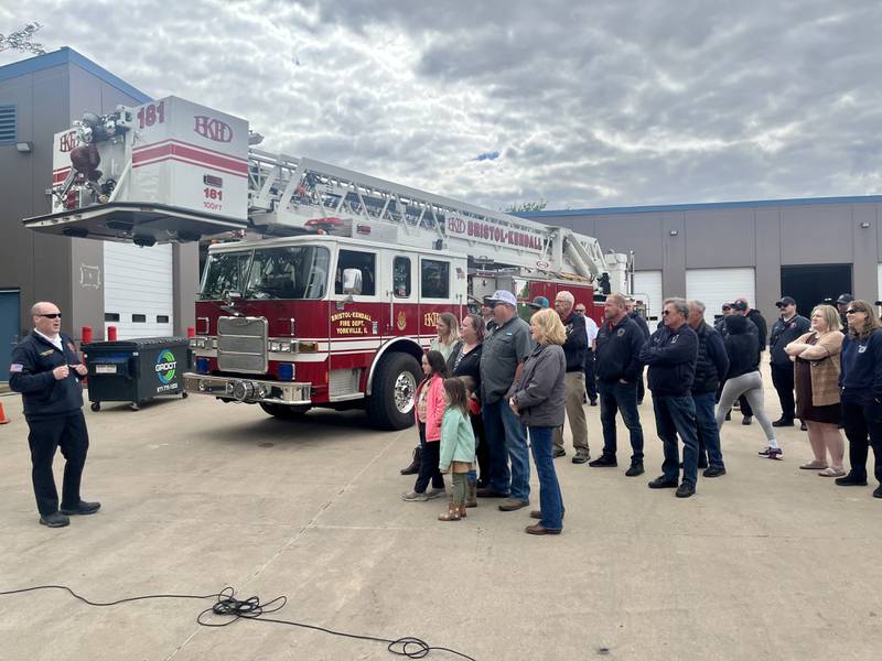 Bristol Kendall Fire Protection Chief Jeremy Messersmith dedicates the department's new training facility to the legacy of Assistant Chief Timothy Fairfield. Fairfield's family, including his son Lieutenant Brandon Fairfield, are surprised by the dedication. The department's fire crew gathers in applause.
