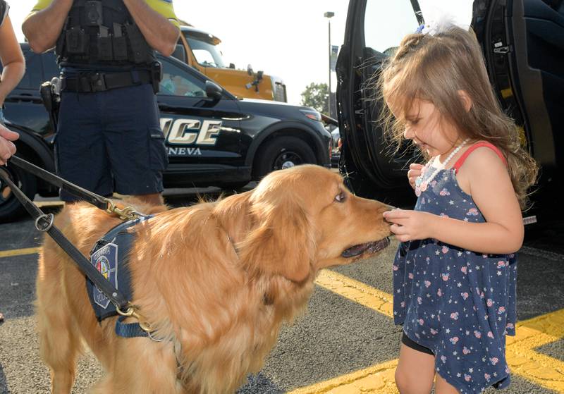 Saige Krueger, 2 feeds Geneva Police Comfort dog "Tommy" a treat during Geneva's first National Night Out event on Tuesday, Aug 5, 2025 in Geneva.