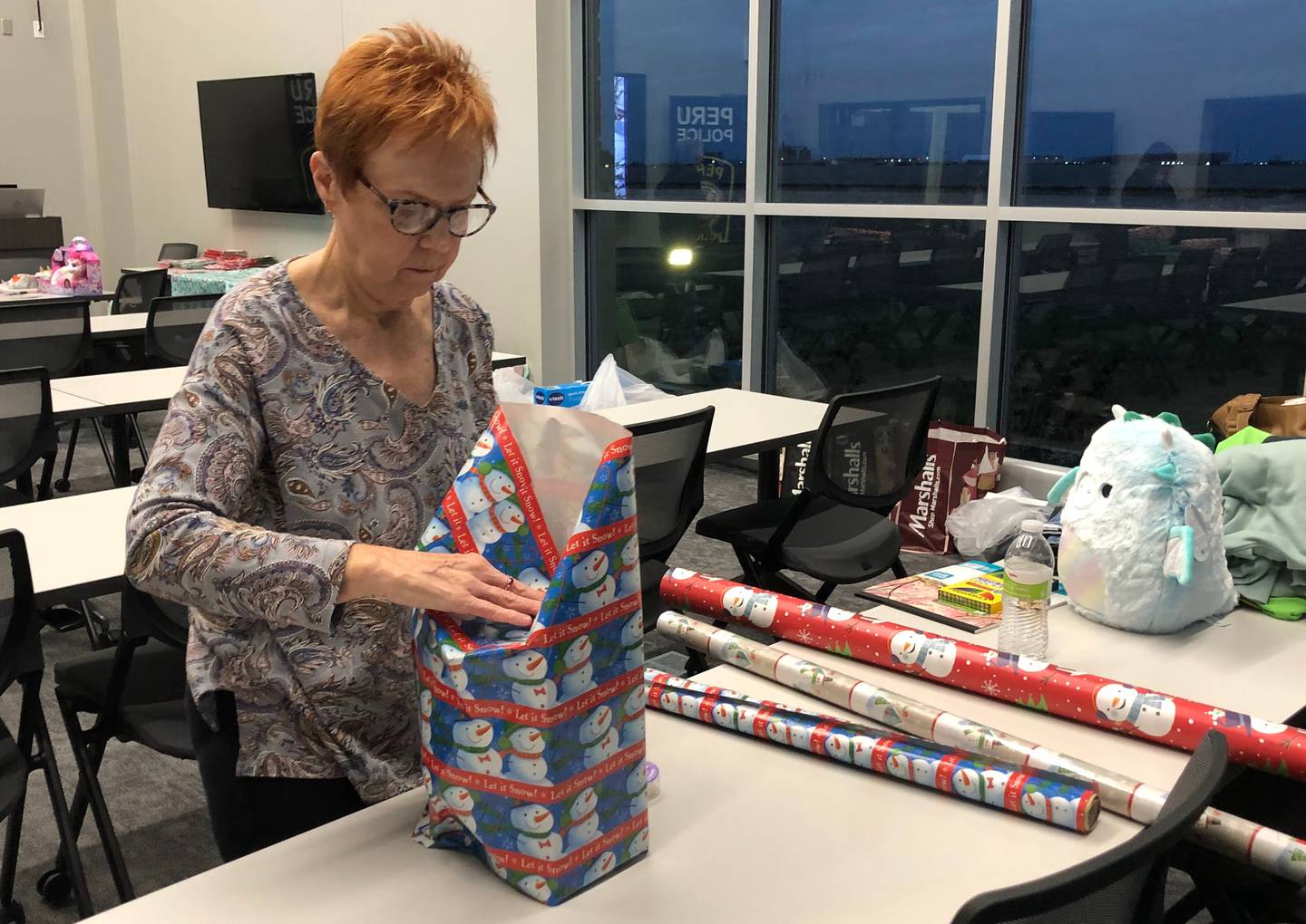 Peru resident Kathy Edens helps wrap Christmas presents for the Red and Blue Christmas for Kids fundraiser at the police department on Friday, Dec 2, 2022.