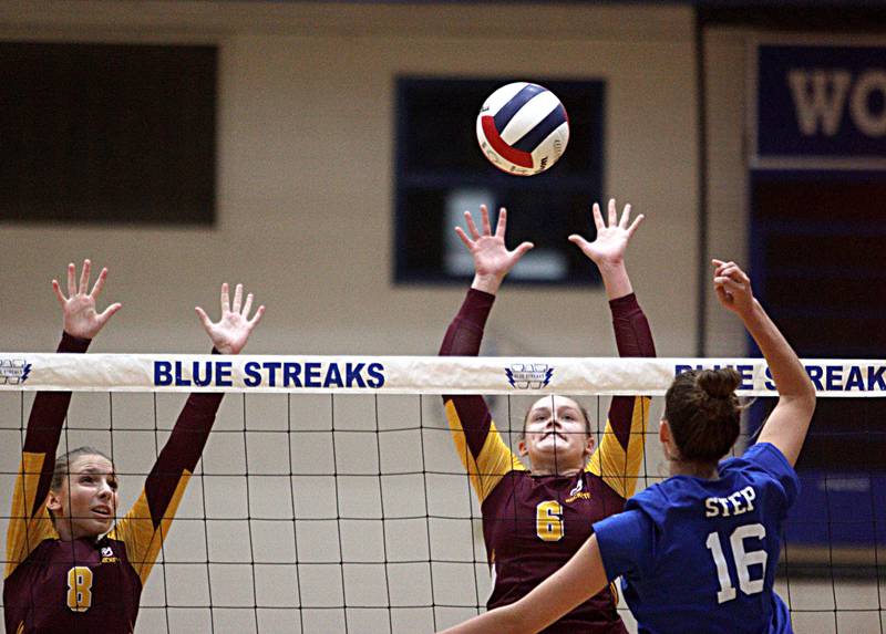 Richmond-Burton’s Dani Hopp, left, and Elissa Furlan, center, block as Woodstock’s Hallie Steponaitis hits the ball in varsity volleyball at Woodstock Monday night.