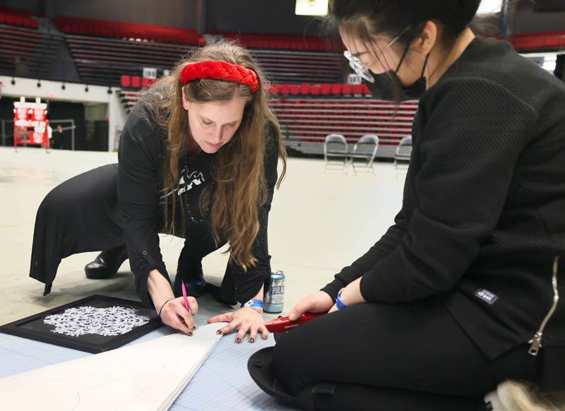 Jessica Labatte, Northern Illinois University associate professor of art, (left) and  photography student Qiming Ruan, a senior, draw out a design on the giant paper snowflake they are making along with other students in the photography department Tuesday, March 29, 2022, in the Convocation Center at NIU in DeKalb. The students are attempting to break the world record for the largest paper snowflake.