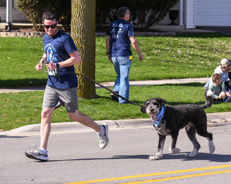 Brett Wolf of Lombard runs with his Burnie doodle dog Franklin, 3, during the Mustang Trot race on Sunday April 14, 2024, held at Downers Grove South High School.