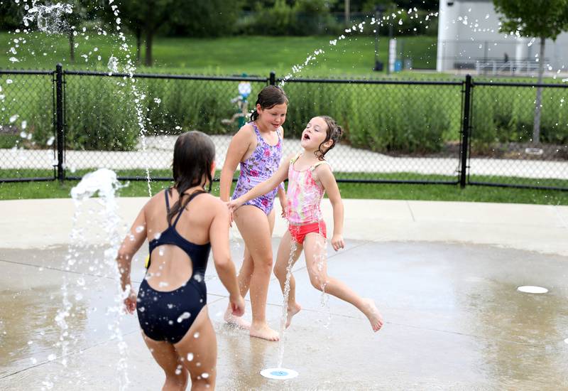 (From left) Emily Gillette, 10, of Brookfield, Essie Amara, 9, of Lombard and Ingerid Amara, 6, of Lombard play in the water at the Gordon Park Splash Pad in La Grange as temperatures hit the 90s on Friday, July 28, 2023.