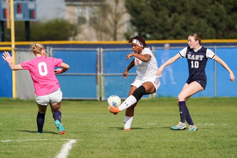 Oswego’s Jordyn Washington (18) shoots the ball against Oswego East's Morgan Dick (10) and Madelynn McGregor (0) during a soccer match at Oswego East High School on Tuesday, April 23, 2024.