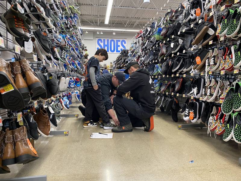 Troy Opyd, an EMT from Marseilles, helps Kash T. try on a new pair of shoes.