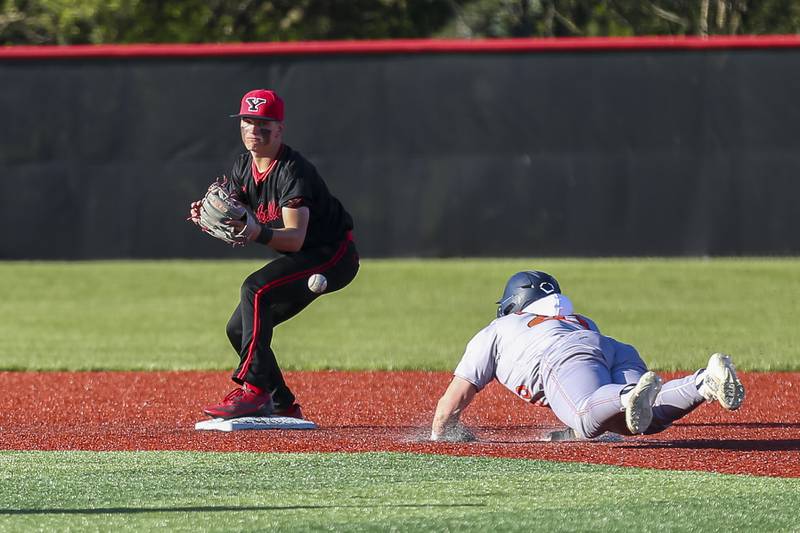 Oswego's Dylan King (20) slides into third after the ball gets away from Yorkville's Justin Giese (8) during baseball game between Oswego at Yorkville. Thursday, May 8, 2025 in Yorkville.