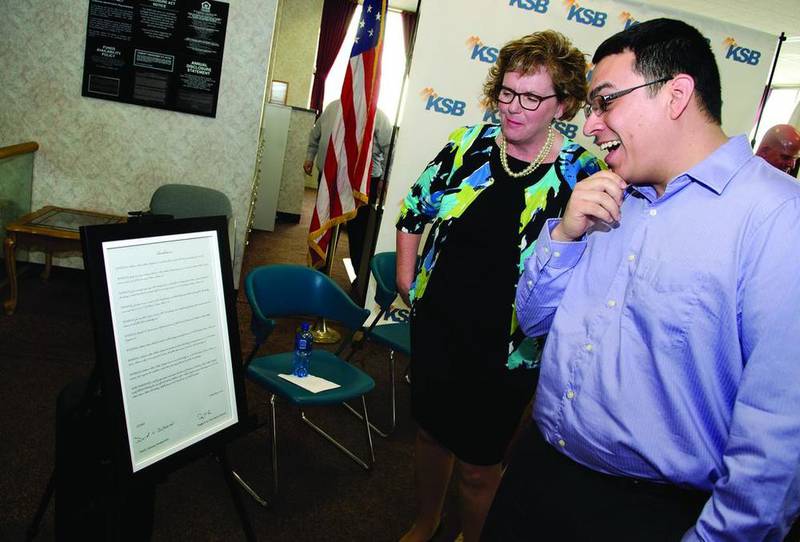 Jan Woodward, market president of Midland States Bank, and Dixon Mayor Li Arellano Jr. look over a resolution proclaiming a change in the name of the former Midland States Bank building to the KSB Lovett Center. KSB Hospital on Friday announced it is buying the building at 101 W. First St. to house its community wellness center and financial departments.
