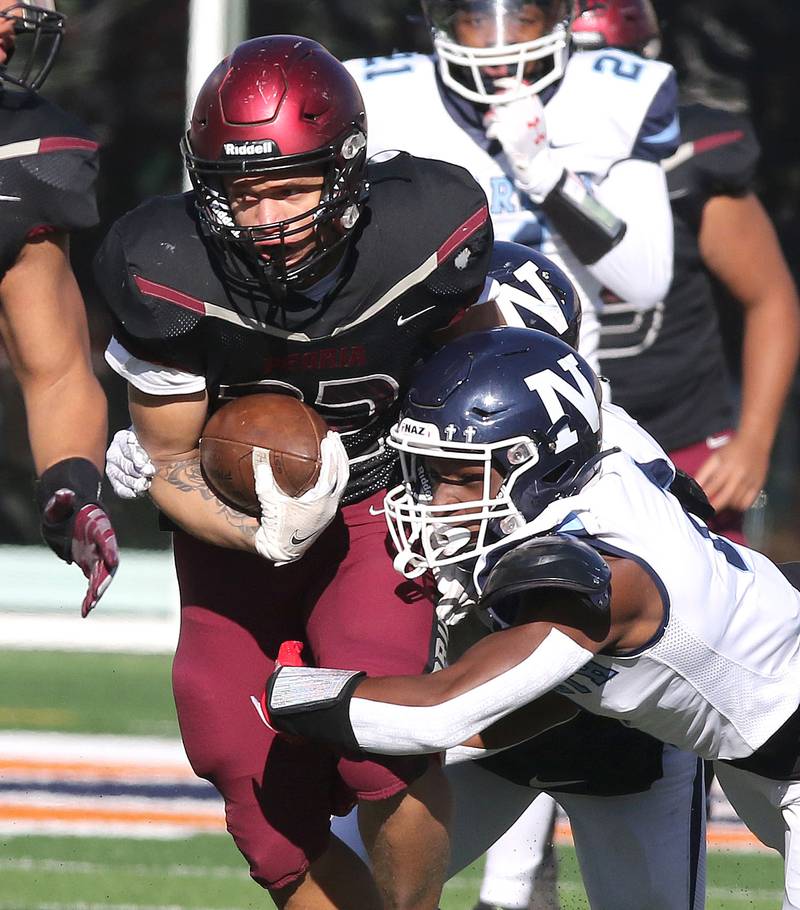 Peoria's Frank Odom tries to break free from Nazareth's Justin Taylor during their IHSA Class 5A state championship game Saturday, Nov. 26, 2022, in Memorial Stadium at the University of Illinois in Champaign.