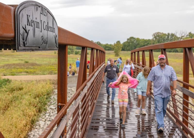 Guests walk across the Kevin Coleman Bridge for the first time after the ribbon cutting ceremony at 501 3rd Street on September 20, 2025 in Hennepin.