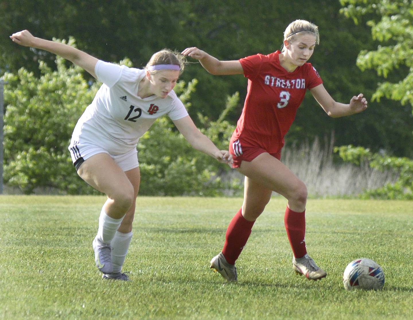 La Salle-Peru’s Avalyn Edwall (12) and Streator’s Joey Puetz (3) race to the ball Friday, May 16, 2025, at the James Street Recreation Area in Streator.
