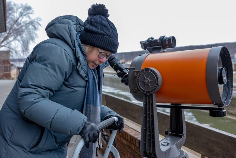 A visitor looks through a spotting scope to view a perched bald eagle on Plum Island on January 24, 2026 at the Illinois Waterway Visitors Center. The location was later shut down early due to having no power.
