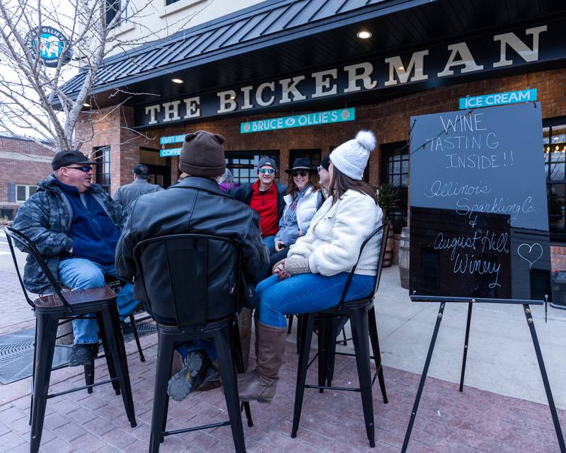 Friends enjoy wine gathered around table at the wine walk on Feb. 14, 2026 on Mill Street in Utica.
