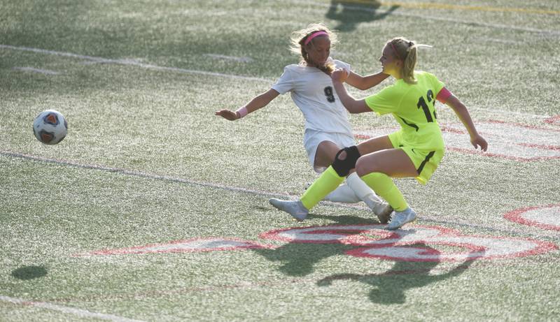 Richmond-Burton's Jordan Otto (13) sends the ball past  Quincy Notre Dame's Avery Keck during Saturday’s IHSA Class 1A state girls soccer championship game at North Central College in Naperville.