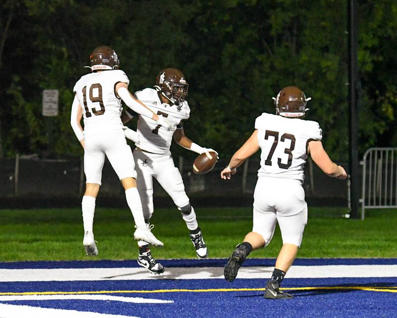 Joliet Catholic's HJ Grigsby (center) celebrates in the end zone with teammates Drew Wills (19) and Travis Peterson (73) after running in for a touchdown drive during the first quarter on Friday Sept. 22, 2023, at St. Francis in Wheaton,.