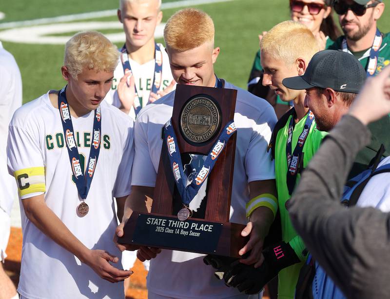 Coal City players admire their trophy Friday, Nov. 7, 2025, after their Class 1A state third place win over Chicago Academy at Hoffman Estates High School.