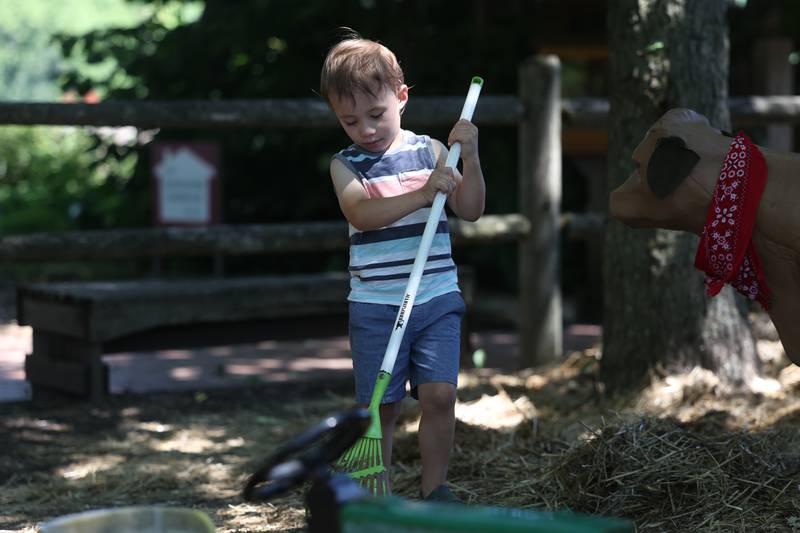 Grayson Caffle, 3-years old of Manhattan rakes hay for the cow at the Children’s Garden in Elwood. The Children’s Garden in Elwood recently celebrated their 25th anniversary. Saturday, July 9, 2022 in Elwood.