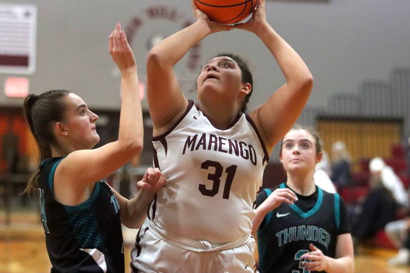 Marengo’s Ariana Rodriguez, center,  battles Woodstock North’s Alyssa Martin in varsity girls basketball on Tuesday, Dec. 2, 2025, at Marengo High School in Marengo.