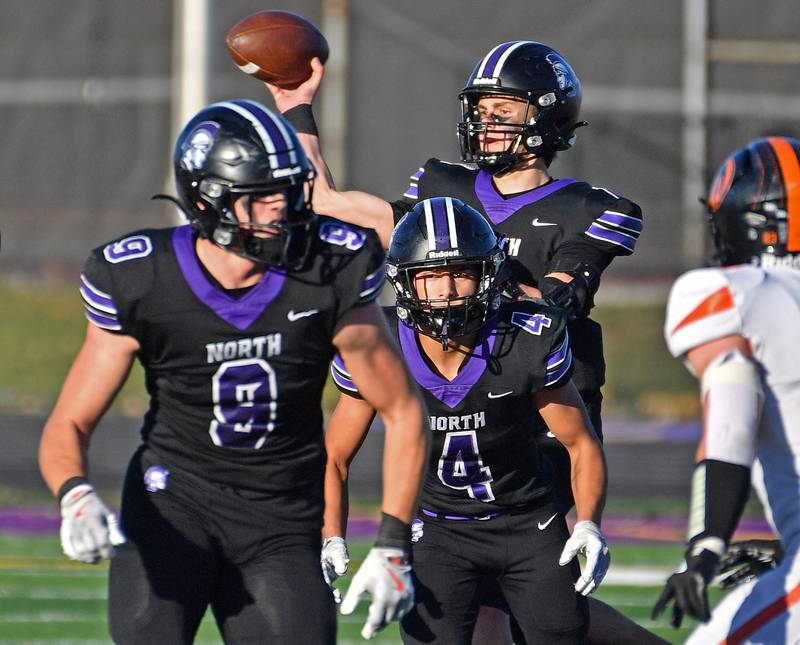 Downers Grove North quarterback Owen Lansu passes the ball from behind blockers Will Vala (9) and Caden Chiarelli (4) during a Class 7A quarterfinal game on November 15, 2025 at Downers Grove North High School in Downers Grove .