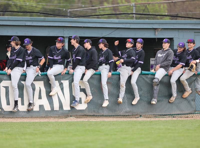 Downers Grove North players sit on the dugout fence between innings during the varsity baseball game between Downers Grove South and Downers Grove North in Downers Grove on Saturday, April 29, 2023.