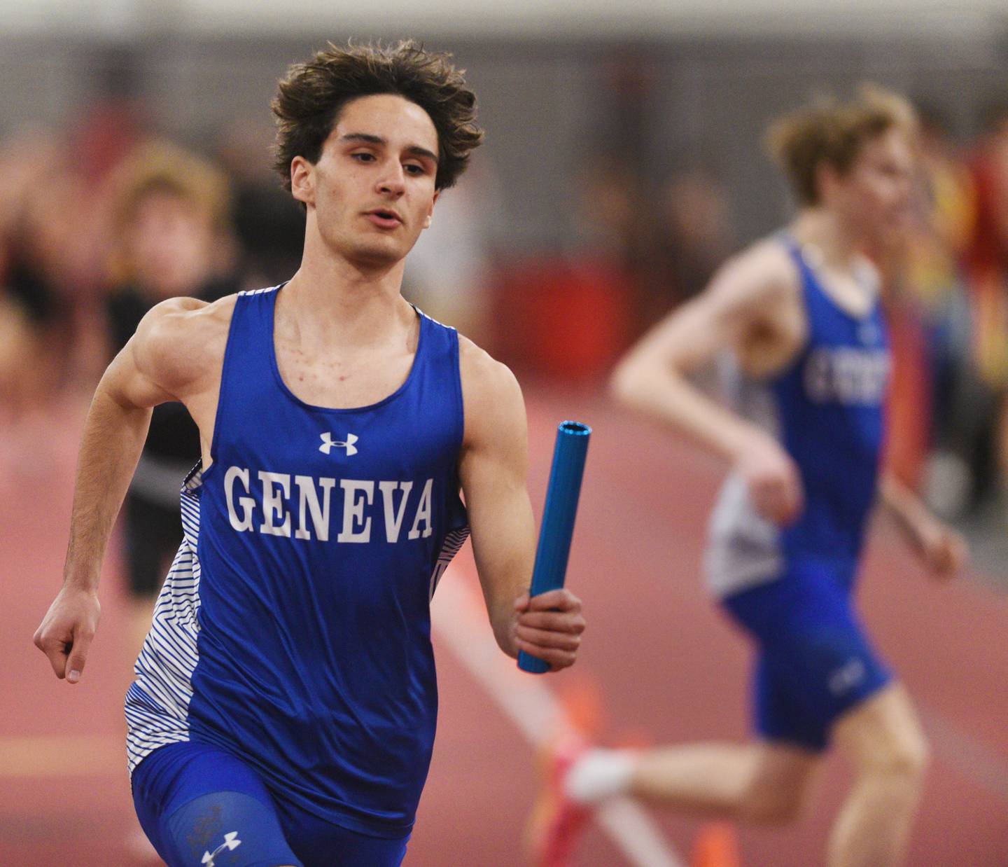 Geneva anchor Parsa Manafi carries the baton after taking it from teammate Luke Gaston as the Vikings head toward a victory in the 3,200-meter relay during the DuKane Conference indoor track meet at Batavia High School on Friday, March 21, 2025.