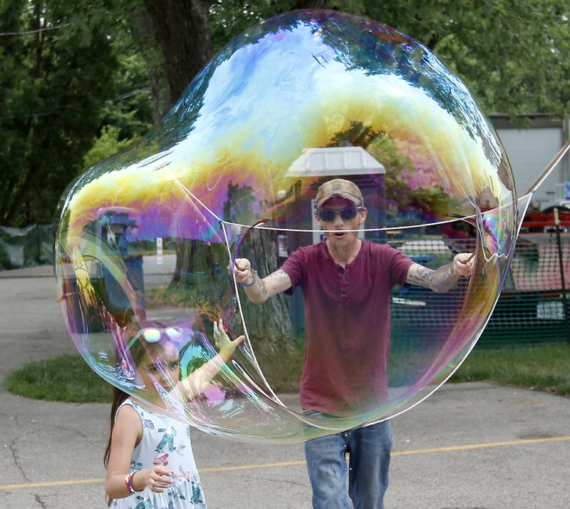 Jonathan Sutter, of Wonder Lake and his daughter Jade Cox, make a giant bubble  during Lakeside Festival Friday, June 30, 2023, at the Dole and Lakeside Arts Park in Crystal Lake.