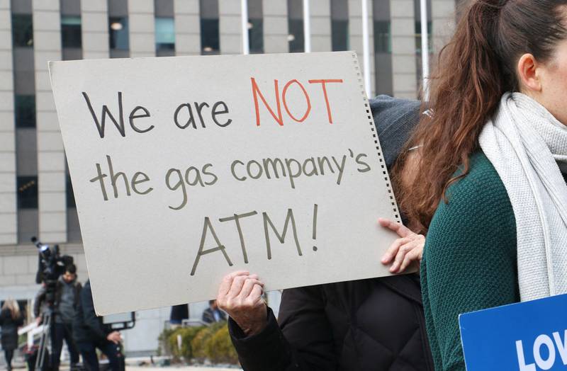 A demonstrator holds a sign reading, “We are NOT the gas company’s ATM!” at a protest held by consumer, environmental and community activists on Jan. 6, 2026. The group was criticizing Peoples Gas’ filing that sought to raise gas delivery rates in 2027.