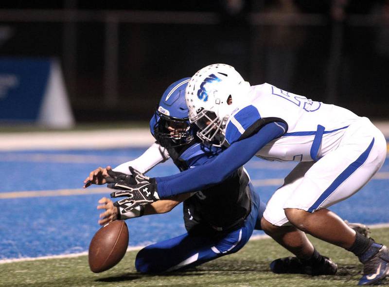 Geneva quarterback Kyle Evert (left) and St. Charles North's Henry Kellogg go after a loose ball that led to a St. Charles North safety during a game at Geneva on Oct. 14. The North Stars won 30-3 and eliminated the Vikings from postseason consideration.