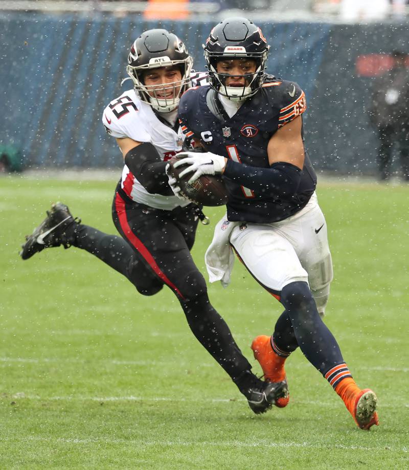 Chicago Bears quarterback Justin Fields runs away from Atlanta Falcons linebacker Kaden Elliss during their game Sunday, Dec. 31, 2023, at Soldier Field in Chicago.