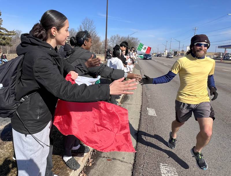A passing jogger supports DeKalb High School students as they protest Tuesday, Feb. 10, 2026, on Sycamore Road in front of Hopkins Park in DeKalb. The students walked out of school Tuesday to protest against ICE involved violence and arrests.