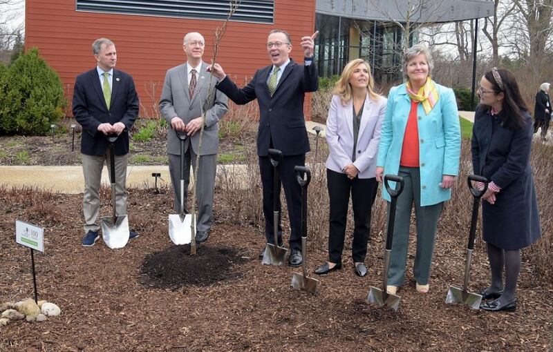 Gerard Donnelly, president and CEO of The Morton Arboretum, points toward a fully grown linden tree similar to one planted in front of him at an Earth Day ceremony to launch a tree planting initiative in honor of the arboretum's 100th anniversary. U.S. Reps. Sean Casten and Bill Foster joined several state lawmakers at the tree-planting kickoff. (Rick West | Staff Photographer)