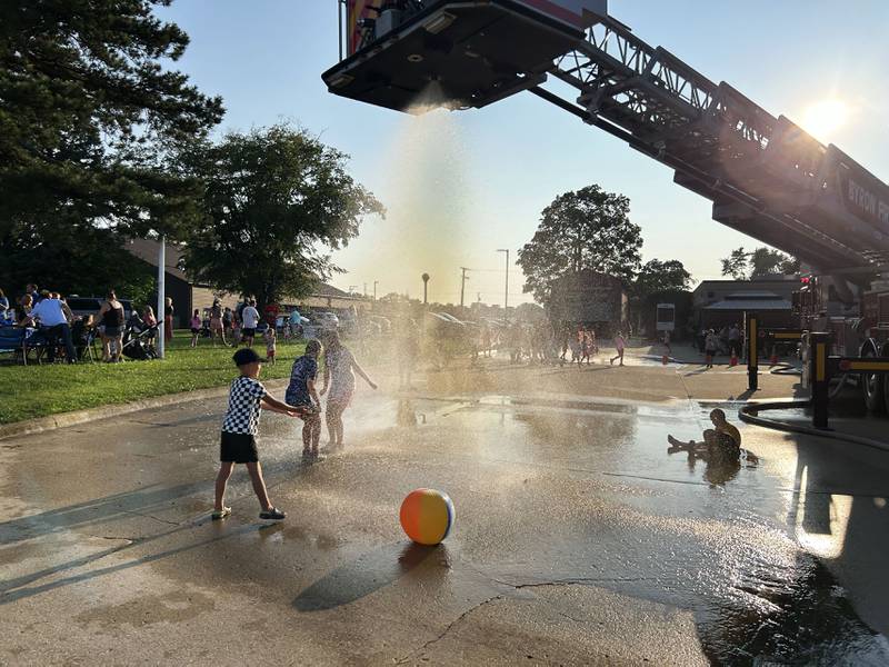 Kids run through a water spray compliments of the Byron Fire Department at the Ogle County Sheriff's Department and Byron Police Department's National Night Out in Byron  on Tuesday, Aug. 5, 2025. Other agencies also took part in the evening event.