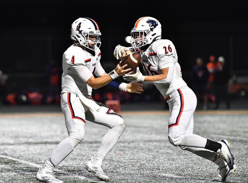 Oswego's Drew Kleinhans (4) hands the ball off to Dekker Zelensek (26) during the conference game against Minooka on Friday, OCT. 10, 2025, at Minooka.