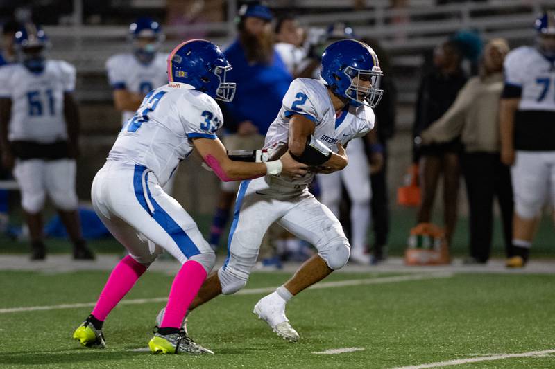 Joliet Central's Paul Slick hands off the ball to Christian Smith  during a game against Plainfield Central on Friday Oct. 11, 2024 at Plainfield Central High School