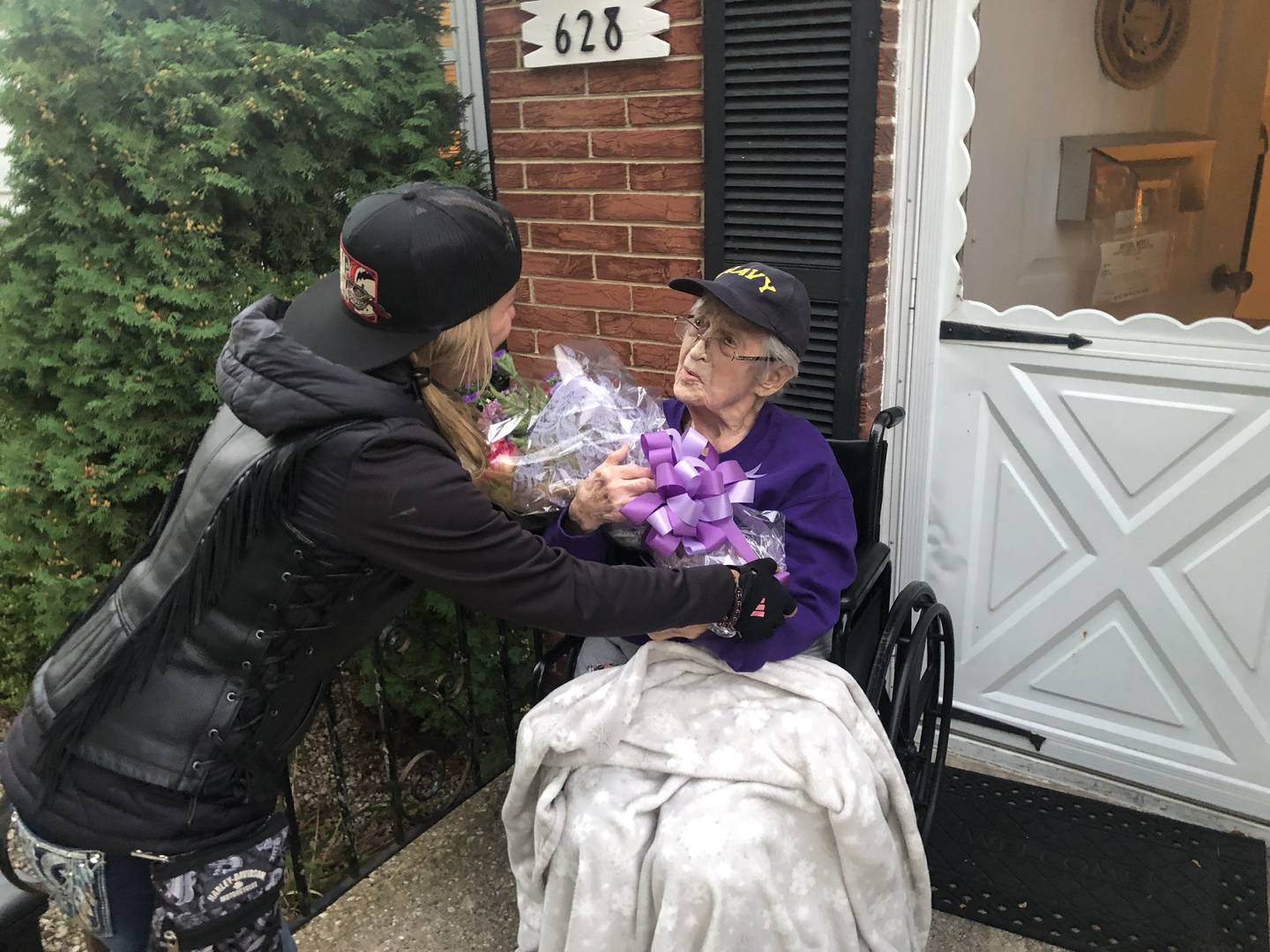 Sherry Buchholz delivers a bouquet to Lorraine Egan for the WW2 veteran's 102nd birthday. Buchholz organized the motorcycle parade past Egan's home on Sunday, Sept. 29, 2024.