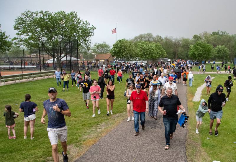 Spectators and competitors run to shelter after a lightning delay was announced during the Dukane Conference Boys Track and Field Meet hosted by Lake Park High School in Roselle on Friday, May 16, 2025.