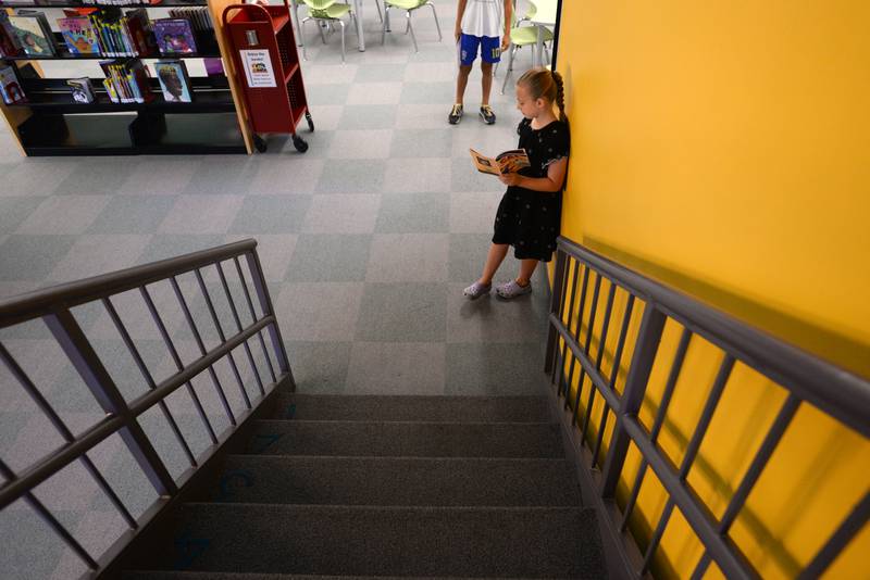 Addison Januszyk of La Grange Park takes time to read a book while attending the La Grange Park Library Grand Reopening Saturday Aug 3, 2024.