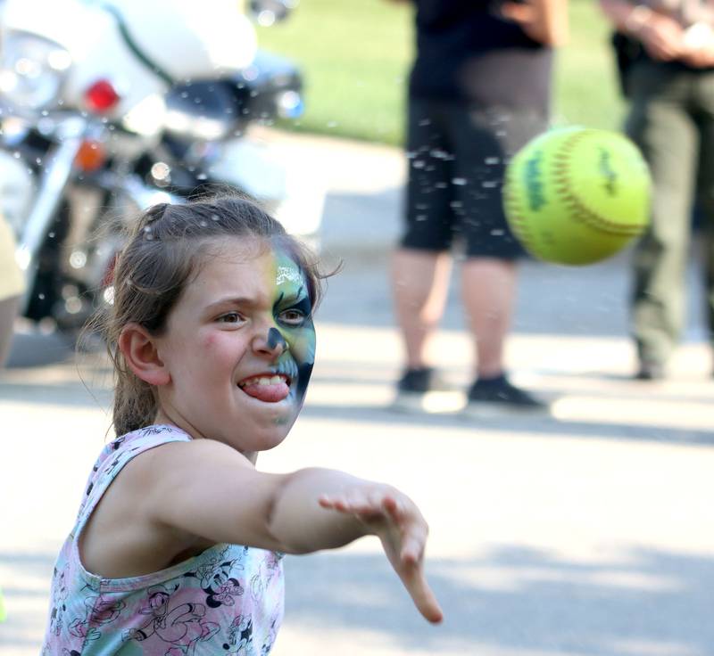 Aurora Huber, 10, of Crystal Lake fires a softball at the dunk tank target during National Night Out activities in downtown Crystal Lake. on Thursday, Aug. 7, 2025.