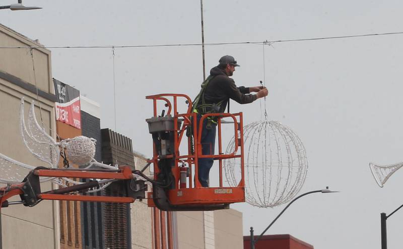 A worker with the City of La Salle, hangs Christmas decorations above First Street on Thursday, Oct. 16, 2025 downtown La Salle. The inaugural Frosty on First event is schedule for Nov. 7-8, 2025 downtown La Salle. The festival will feature an ice skating rink with rental skates, an inflatable snowman bounce house, an inflatable maze and a Snow-Zilla slide.