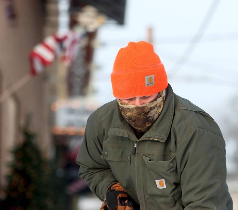 Mike Harrah is bundled up as he clears the sidewalk near the D5 Ranges in Marengo Friday morning.