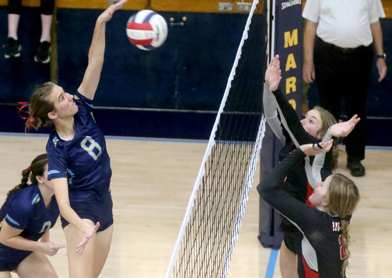 Marquette's Mary Lechtenberg spikes the ball past Woodland's Peyton Bradbury and Grace Longmire on Thursday, Oct. 19, 2023 at Bader Gym.