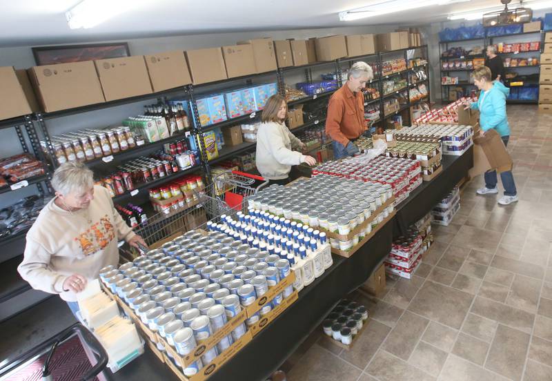 Volunteers pack canned corn, ranch dressing, green beans, stuffing, gravy and other items to make Thanksgiving dinner  for the annual Thanksgiving distribution on Wednesday, Nov. 20, 2024 at the Hall Township Food Pantry in Spring Valley.