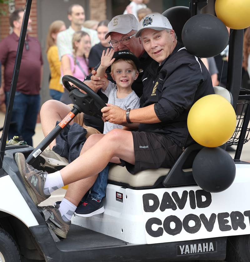 Parade Grand Marshall David Coovert, along with his grandson, also David Coovert, 4, wave as they head down State Street Wednesday, Sept. 20, 2023, during the Sycamore High School homecoming parade.