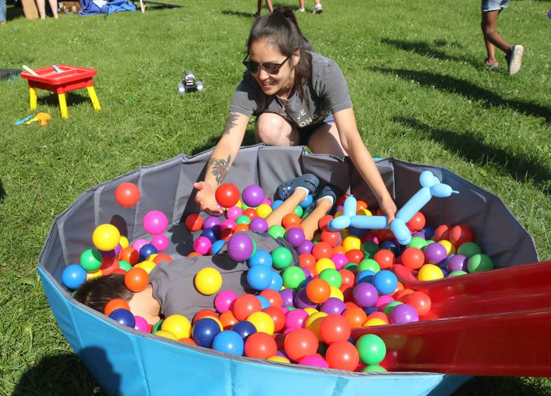 Mackenzie Crowell, from Sycamore, buries her son Oliver, 5, in a ball pit at the Westside Children’s Therapy booth during the Family Fun Fest Wednesday, July 17, 2024, at Hopkins Park in DeKalb.