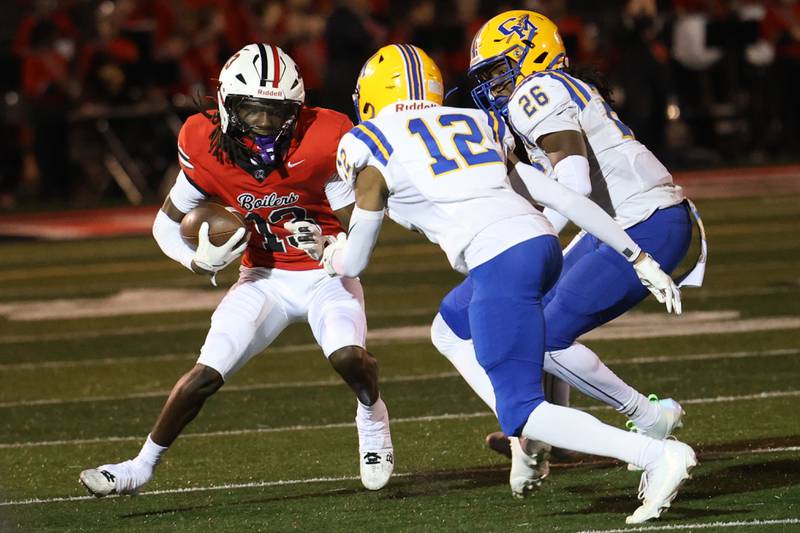 Bradley-Bourbonnais' Lyzale Edmon, left, evades Crete-Monee's Landon Haynes (12) and Kamal Bryant during a game at Bradley-Bourbonnais Friday, Sept. 5, 2025.