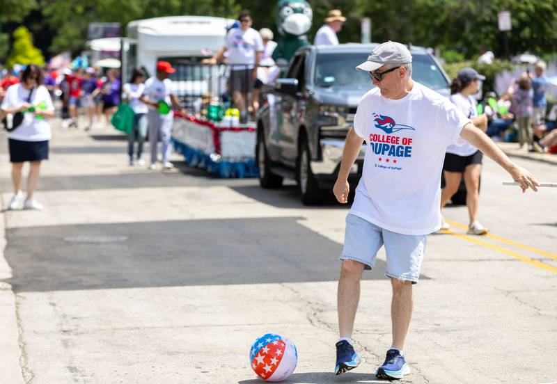 A college of DuPage representative kicks a loose beach ball back to the spectators who dropped it during Glen Ellyn’s “4th of July Parade” on Friday, July 4, 2025.