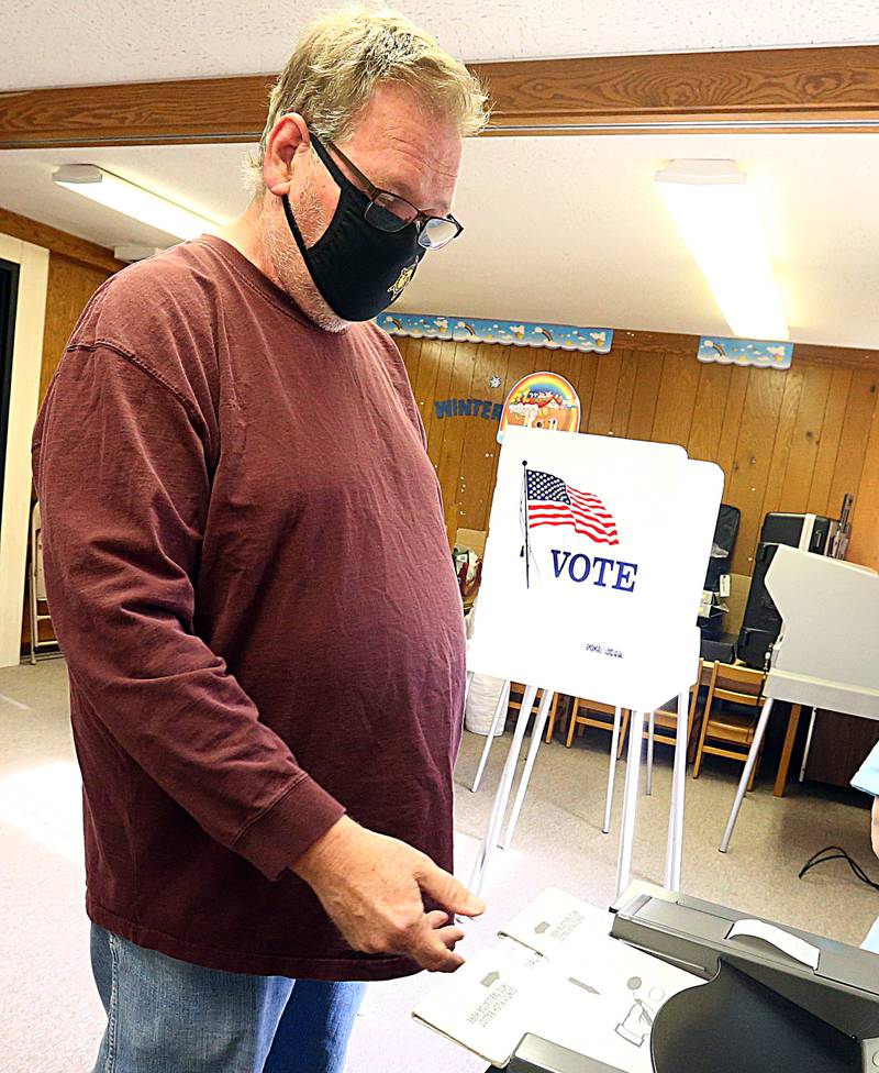 Ken Hanford, of Peru, inserts his ballot into a voting machine at St. Johns Lutheran Church in Peru on Tuesday April 6, 2021.