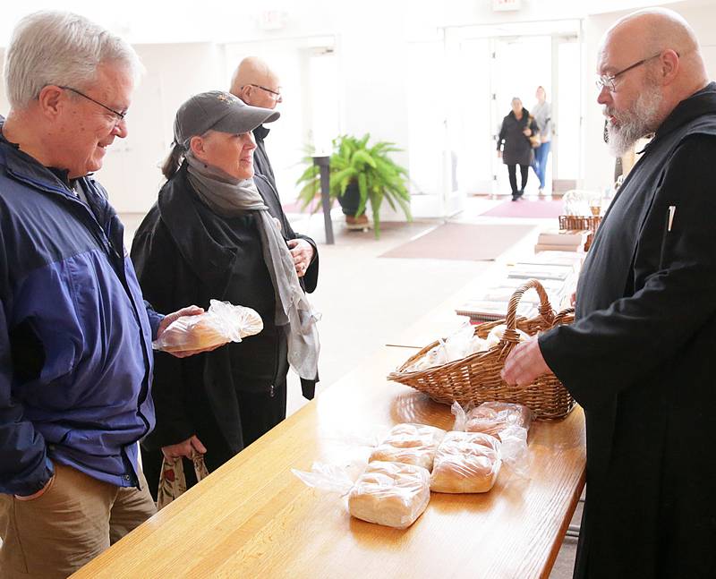 Jim and Kathy Harvy, of Minooka, purchases bread rolls from Father Dominic Garramone, OSB, at the annual Christmas Monks market inside The Abbey Church at Saint Bede Academy. Father Dominic, is the author of several cookbooks, and bakes the bread using mash potatoes and several other ingredients.