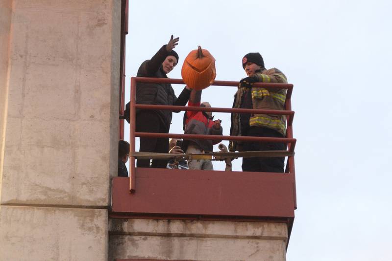 Benjamin Warner 3, of Byron, gets some help from his mom Kelsey to push his Jack-O-Lantern off the fire tower during the Byron Fire Department's Pumpkin Smashing Event on Wednesday, Nov. 1, 2023.